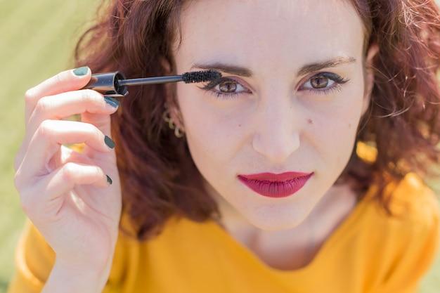 Woman applying mascara outdoors