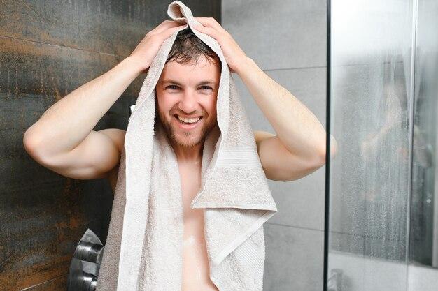 Smiling man drying hair with towel in bathroom